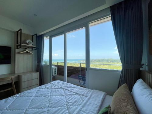 a bedroom with a bed and a large window at Sea View Apartment at Nuvasa Bay Kalani Tower in Nongsa Area in Telukmataikan