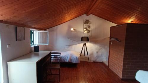 Cette chambre comprend un lit et une table avec un tripode. dans l'établissement Orion Guesthouse Telhado, à Fundão