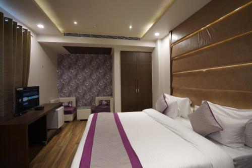 um quarto de hotel com uma cama grande e uma televisão em Nature's Nest em Nova Deli