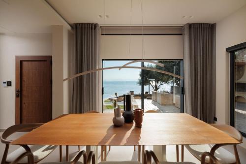 a dining room with a table and a view of the ocean at Nisos Villa Emerald in Kornáta