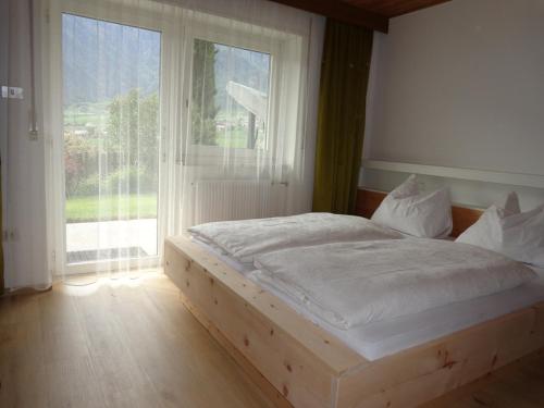a bed in a room with a large window at Haus Talblick "Neuräutl" Ferienwohnung 2 in Naturno