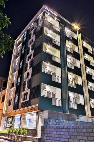 a tall building with lights on in front of it at The Auberge Boutique Hotel - Manyata Tech Park in Bengaluru