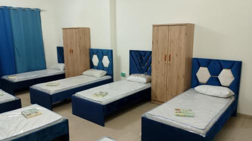um quarto com 4 camas com cabeceiras azuis e almofadas azuis em Cornich ajman em Ajman