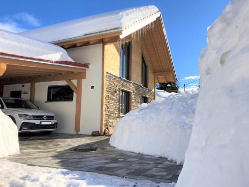 a pile of snow next to a house with a car at Alpenchalet Allgäu in Oy-Mittelberg