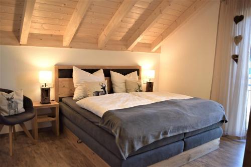 a bedroom with a large bed and a chair at Alpenchalet Allgäu in Oy-Mittelberg