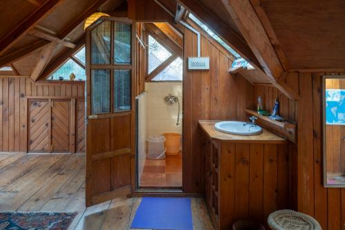 un bagno con lavandino in una casa di legno di Naddi Castle a McLeod Ganj