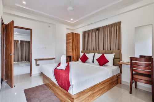 a bedroom with a bed with red pillows and a desk at The Auberge Boutique Hotel - Manyata Tech Park in Bengaluru