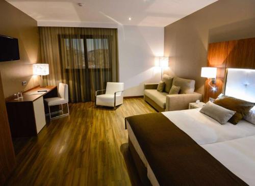 Habitación de hotel con cama y sala de estar. en Gran Hotel Botánicos en Teruel