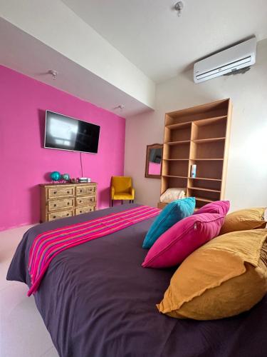 una camera da letto con un grande letto con una parete rosa di Recámara con terraza y Firepit privados a Santiago