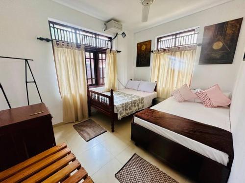 a bedroom with two beds and a bench in it at Casa Winnie in Kelaniya