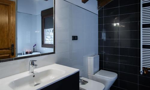 a bathroom with a sink and a toilet and a mirror at Casa Rural O Fraginal in Guasillo