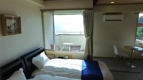 a bedroom with a bed in front of a window at HOTEL GREEN PLAZA SHODOSHIMA - Vacation STAY 51989v in Ikisue