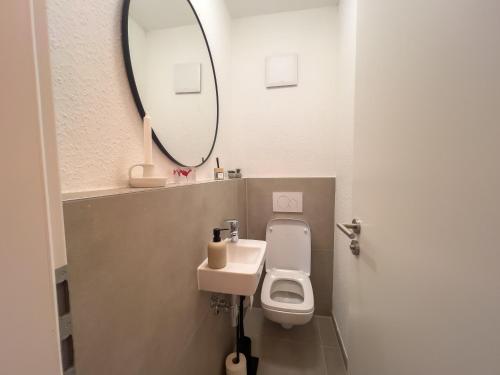 a bathroom with a toilet and a sink and a mirror at SCHLOSSBERG RESIDENCES - Design City-Apartment im Herzen der Weinstraße in Neustadt an der Weinstraße