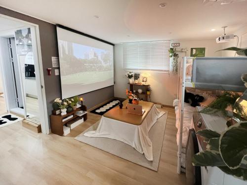 sala de estar con mesa y pantalla grande en 홍대 입구역 7min, Designer house, 대형빔, 2R, 포토존, 신축, 최대5인 en Seúl