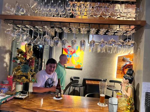 two men standing behind a bar with wine glasses on the wall at PAPABO Adventure Village in Moalboal