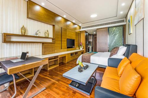 广州Poly Pivot International Aparthotel Guangzhou East Railway Branch - Free Shuttle Bus to Canton Fair Complex During Canton Fair Period的一间卧室，配有一张床、一张书桌和一张沙发