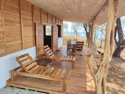 porche de una cabaña de madera con sillas y mesa en Casa Lagarto Beachfront, en Venado