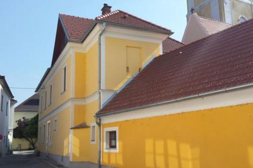 ein gelbes Gebäude mit braunen Dächern auf einer Straße in der Unterkunft Wachau - Angenehm ruhiges Zimmer 5 in Mautern