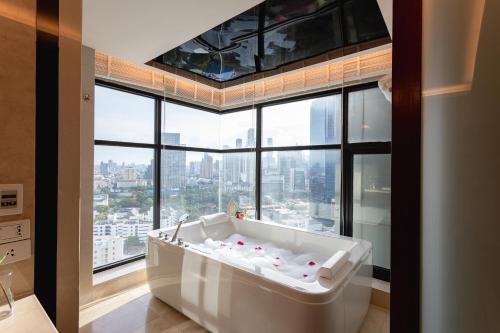 a bath tub in a room with a large window at AETAS lumpini in Bangkok