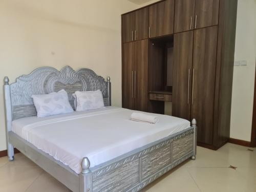 a bedroom with a large bed with a wooden cabinet at Flix holdings- Apa apartments mombasa in Mombasa