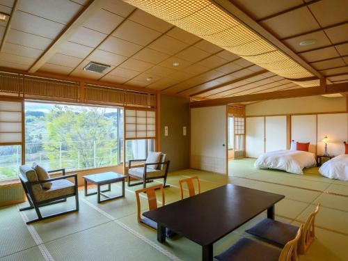 Sagaeにある寒河江温泉 ホテルシンフォニーアネックス YAMAGATAのベッド、テーブル、椅子が備わる客室です。