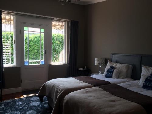 a bedroom with two beds and two windows at 30 on Oatlands Road in Grahamstown