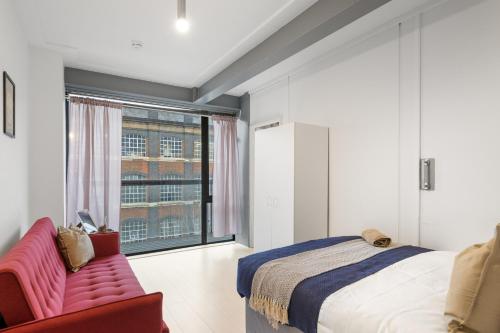 a bedroom with a bed and a chair and a window at LiveStay - Modern Two Bed Apartment in Stratford in London