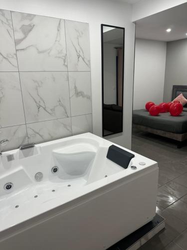a bathroom with a white bath tub with a mirror at Lov’SPA 2 in Fleury-Mérogis