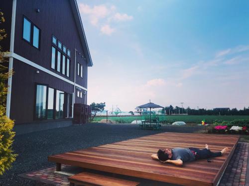 a man laying on top of a wooden bench at Shooting Star the Bed & Breakfast in Furano