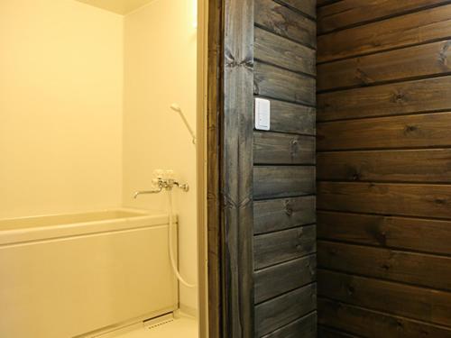 ein Badezimmer mit einer Dusche und einer Holztür in der Unterkunft Japanese Cottage Nagomiya seseragi in Gujō