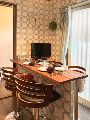 a wooden table with chairs and a clock on the wall at Rakuyado kyotofushimi I in Kyoto