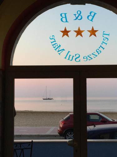 a window with a view of the beach and a boat at Terrazze Sul Mare in Pozzallo