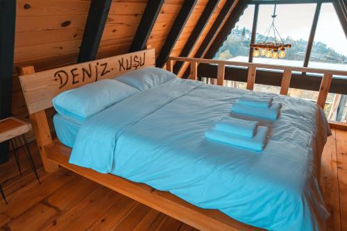 a bed in a cabin with blue sheets and pillows at Denizkuşu Bungalov in Rize