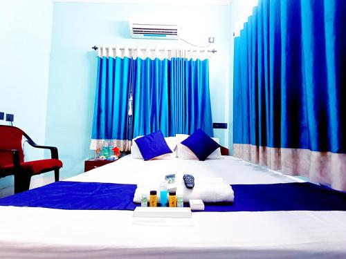 a bedroom with a large bed with blue curtains at The Amber in Durgāpur