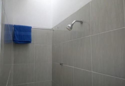 uma casa de banho com um chuveiro e uma toalha azul em OYO 93808 Lincoln Dormitory em Tangerang
