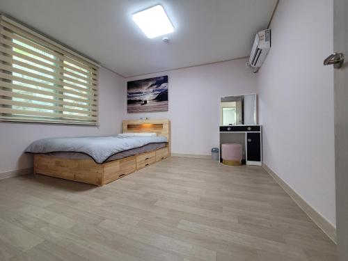 1 dormitorio con 1 cama en una habitación con paredes blancas en 여수 thestay, en Yeosu
