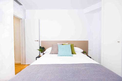 biała sypialnia z dużym łóżkiem z niebieskimi poduszkami w obiekcie Apartamentos turísticos Plaza sevillano w mieście Cartagena