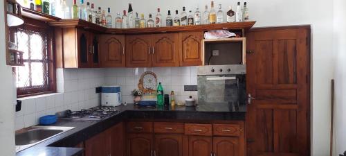 una cocina con armarios de madera y botellas en la pared en Fernando Residencies - wennappuwa, en Wennappuwa