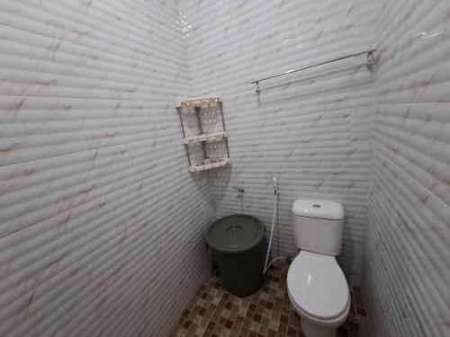a white bathroom with a toilet and a trash can at OYO 93814 Amanda Homestay in Bandar Lampung