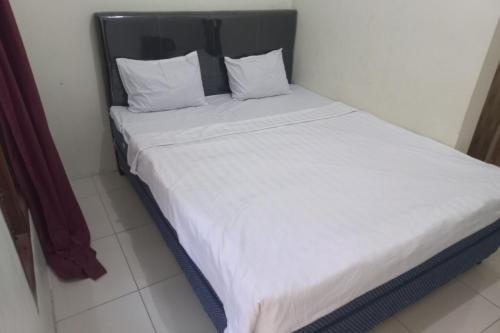 - un lit avec des draps et des oreillers blancs dans l'établissement SPOT ON 93815 Chimi Rumah Kost, à Purwokerto