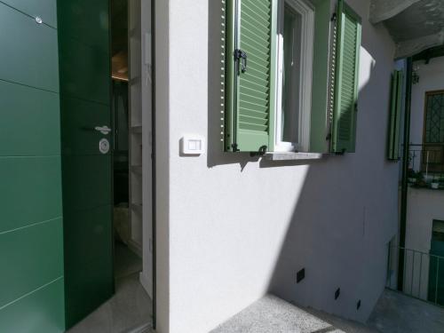 y baño con ducha y ventanas con persianas verdes. en Mamma Ciccia - modern apt in the historic centre, en Mandello del Lario