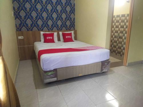 a bed with two red pillows in a room at OYO 93818 Wisma Al Araf Syariah in Palembang