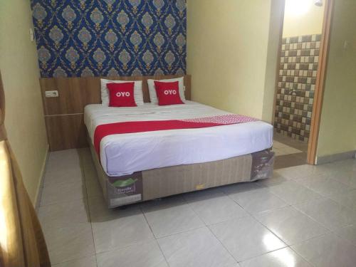 1 cama con 2 almohadas rojas en una habitación en OYO 93818 Wisma Al Araf Syariah, en Palembang