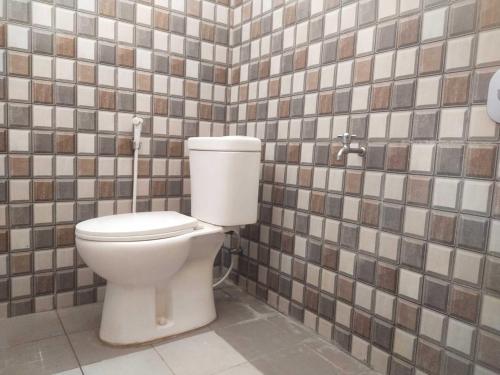 a bathroom with a toilet in a tiled wall at OYO 93818 Wisma Al Araf Syariah in Palembang