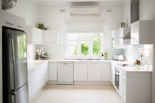 une cuisine blanche avec des placards blancs et une fenêtre dans l'établissement The Whitehouse on Boyce Street, à Taree