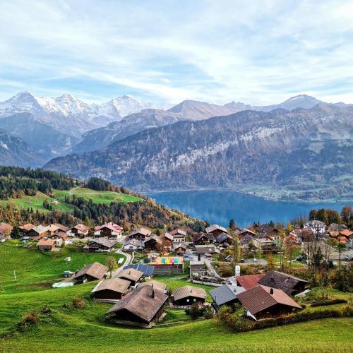 a village with a lake and mountains in the background at Hotelwohnung Superior-Suite in Beatenberg