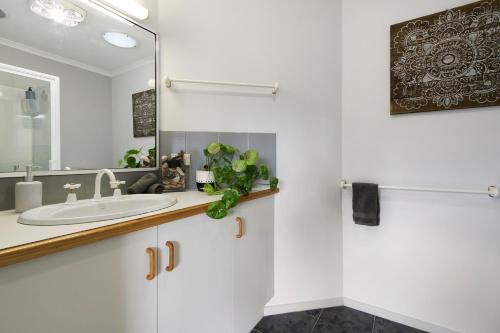 a bathroom with a sink and a mirror at Driftwood Townhouse - Waterfront-Central Location in Lakes Entrance