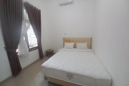 een bed in een witte kamer met een raam bij OYO 93820 Salma Homestay Syariah in Purwokerto