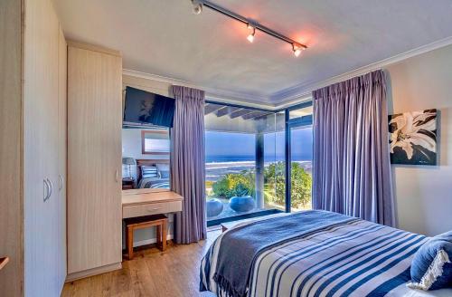 a bedroom with a bed and a desk and a window at Sawubona Guesthouse in Beach View