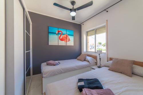 サン・ハビエルにある02224 Apartamento en segunda línea de playaのベッドルーム1室(ベッド2台付)が備わります。壁にはフラミンゴの絵画が飾られています。